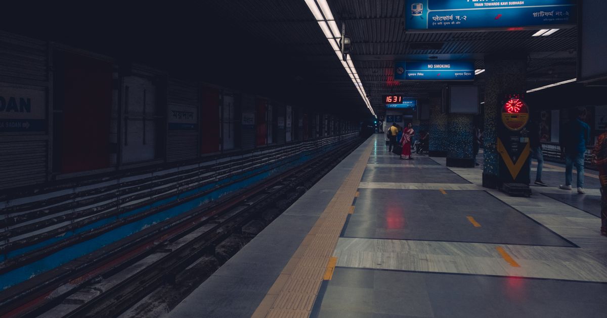 A dimly lit metro station platform with passengers waiting, showcasing urban public transportation.