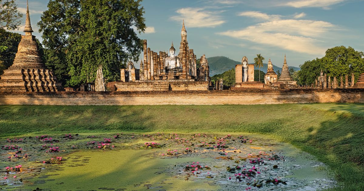 Serene view of ancient temples and blooming lotus pond in Sukhothai, Thailand.